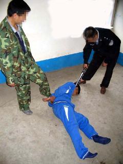 酷刑演示：施暴者將法輪功學員打倒在地，向後反擰雙臂，然後用腳猛踩腰部