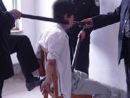 酷刑演示：惡警將法輪功學員反銬在椅子上，用腳踩在手銬上