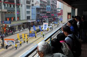 遊行隊伍走在彌敦道上，人行天橋上的民眾也駐足觀看。