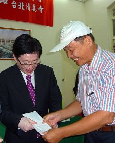 圖：中共宗教局長王作安（左）在拜訪台北清真寺後，收到法輪功學員（右）送的訴狀，王認為是禮物，道謝收下。