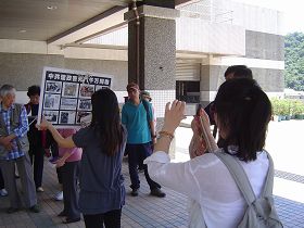 中國遊客拿起相機，拍攝真相展板