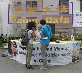 在著名景點勃蘭登堡門前，不斷有人來到法輪功攤位前仔細詢問，並簽名反迫害
