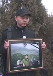 圖為曹東2012年出獄後為妻子下葬時懷抱妻子遺像。