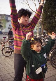 一九九九年四月初，幾個煉功點的近千名法輪功學員在瀋陽和平廣場晨煉──煉功人群中的母女。