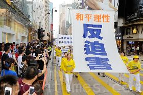 '素琴（左側第一位）參加五月六日香港反迫害遊行時，掌「反迫害」大旗。'