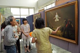 '台灣藝術家黃鉅太（左一）聚精會神聽解說員介紹畫作。'