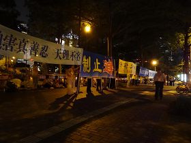'法輪功學員八日傍晚在君悅飯店對面打開各種抗議橫幅，以靜坐、煉功方式表達訴求。'