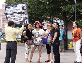 '退休宜蘭教師李光輝正向中國遊客講真相（身著黃色襯衫拿展板）'