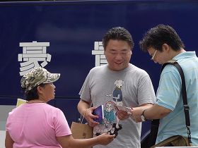 '李香蘭（左一著粉色衣服者）發《九評共產黨》及法輪大法簡介給大陸觀光客'