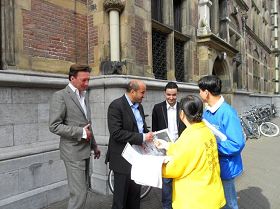 '國會議員馬克齊（Ahmed Marcouch，左二）高興的接過了學員遞上的英文版明慧週報，並向學員了解法輪功信息。'