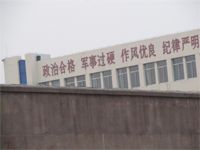 '濰坊市看守所（辦公樓東樓），東樓上標著「政治合格 軍事過硬……」的標語大字，顯示看守所施行的是軍事化管理、並把「政治」放在第一位、「政治」上向中共表態。'