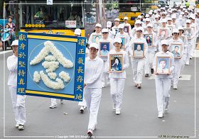 圖4：學員穿著淨白素服，手捧被迫害致死的大陸法輪功學員照片，聖潔肅穆地行進著