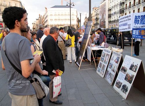 圖1：二零一四年十月三日傍晚，馬德裏市中心的太陽門廣場上，民眾認真閱讀法輪功真相展板