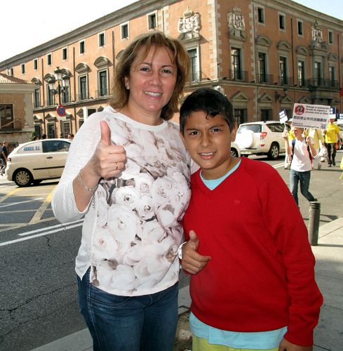 圖3：二零一四年十月四日，法輪功學員在馬德裏舉行遊行，一位小男孩和媽媽一起認真觀看並用iPad拍攝遊行隊伍，伸出大拇指讚歎法輪功