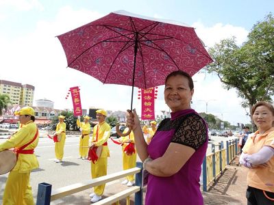 鄧女士開心的撐著雨傘站在路旁觀看遊行。