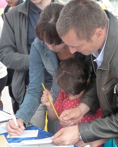 圖2：一家人都來幫忙營救在中國深陷牢獄的法輪功學員，先是母親（左）簽名，然後是父親。