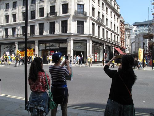 路過的華人看到法輪功學員的遊行隊伍，立即掏出相機或手機攝影和攝像