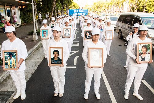 學員衣著淨白素服，手捧被迫害致死的大陸法輪功學員照片，聖潔靜肅行進