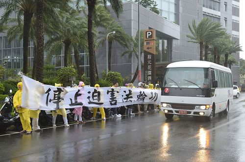 二十三日颱風襲台，強衛車隊至台中市裕元花園酒店，法輪功學員頂著強風暴雨拉著橫幅告訴強衛：「停止迫害法輪功。」