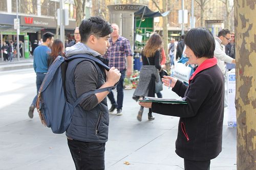 墨爾本大學的香港留學生小黃（左）認真的聽學員講真相