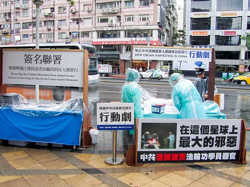 圖1：台北法輪功學員在東區頂好商圈廣場以真人模擬演示行動劇，揭露中共活摘器官販售的暴行，並向路人徵簽舉報江澤民的反人類罪行。