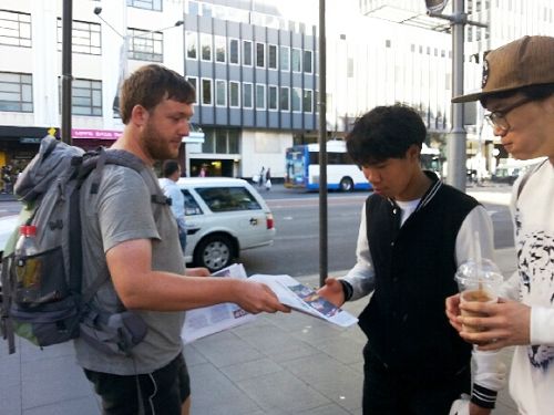 德國遊客菲爾（Phil，左）主動派發揭露中共活摘器官的真相資料給路人