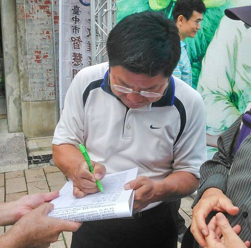 圖說3 台中市文化局副局長施純福正在「刑事舉報江澤民」聯署書上簽名。