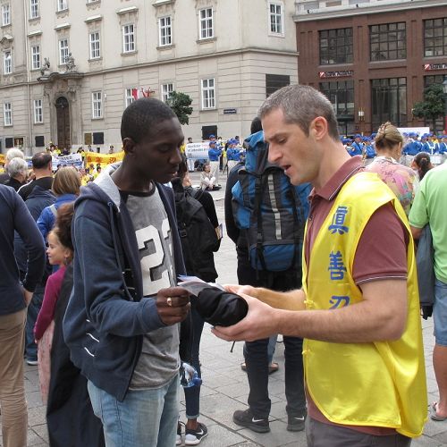 圖：2015年9月19日，歐洲法輪功學員在維也納斯特凡大教堂前廣場舉行反迫害、聲援全球控江集會，意大利法輪功學員安德烈（Andrei）在廣場人群中發傳單並講真相