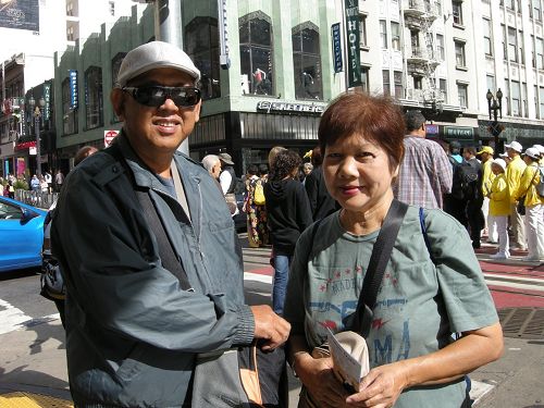圖：馬來西亞華人戴先生和太太不停在給法輪功遊行隊伍拍照。