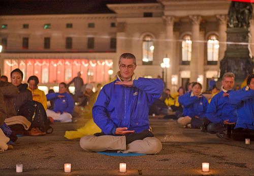 '圖10-11：歐洲法輪功學員在德國慕尼黑的Max-Joseph廣場舉行燭光守夜活動。 祥和場面，吸引不少過往行人駐足了解真相。'