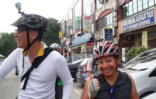 '圖9：一位華裔（左）與友人（右）結伴騎單車的途中，很開心遇到法輪功學員的遊行，並表示非常好！'