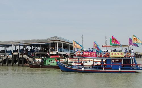 圖8-9：二月十三日下午一時，天國樂團團員乘上一艘主要以七彩繽紛的「法輪大法」旗子裝飾的雙層吉膽島（Pulau Ketam）環島遊船，開始了當天的環島演奏。