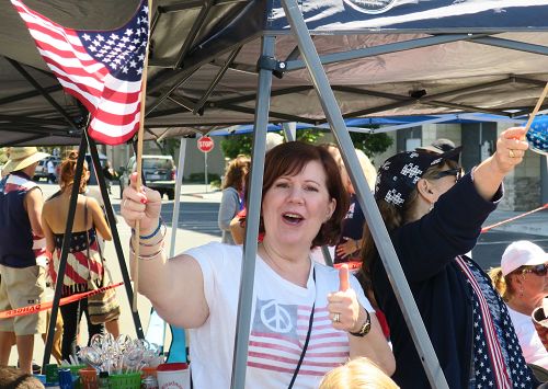 圖11：紅木城居民Tina Ford看到法輪功的隊伍興奮不已，不禁一隻手豎起大拇指，另一隻手搖著美國旗歡呼。