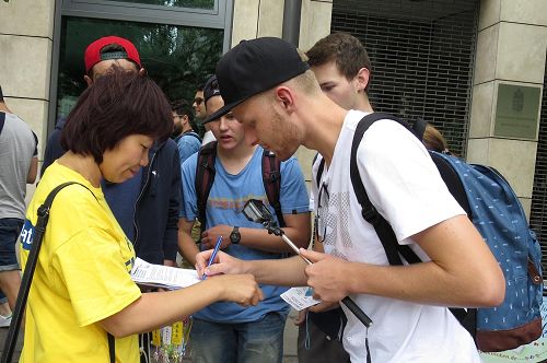 '圖10：來自德國慕尼黑的大學生Simon Strober 和夥伴簽名聲援法輪功學員反迫害。'
