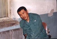 '中新網二零零二年四月一日的圖片顯示：關押的房間內血跡斑斑，劉成軍顯然已無力保持自然坐'