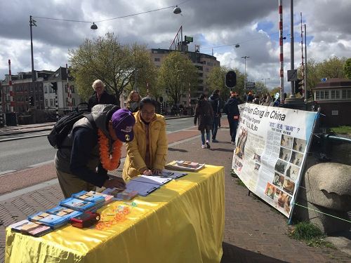 '圖1：法輪功學員在阿姆斯特丹舉辦講真相活動，民眾簽名支持反迫害'