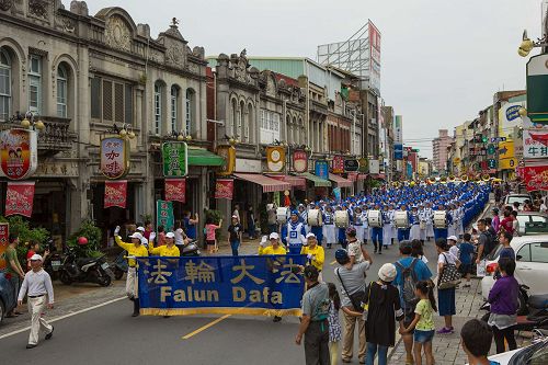 '圖1：台灣法輪大法天國樂團受邀參加了台南市政府舉辦一年一度的「管樂藝術季」開幕大遊行，有不少民眾拿出手機照相留影。'