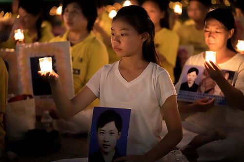 圖4：來自遼寧的十六歲女孩徐鑫洋手捧父親徐大為的遺像。徐大為因為堅持修煉法輪功被中共冤判八年監禁，出獄後十三天離世。