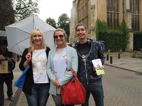 '圖6：波蘭女士和家人遇到正在走過劍橋大學古老建築群的法輪功和天國樂團的遊行隊伍'
