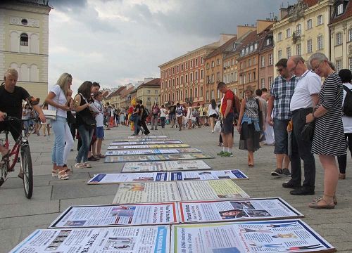'圖9：波蘭市民遊客觀看法輪功真相展板'