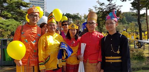 '圖28：印尼法輪功學員黃義任全家身著民族服裝參加遊行'