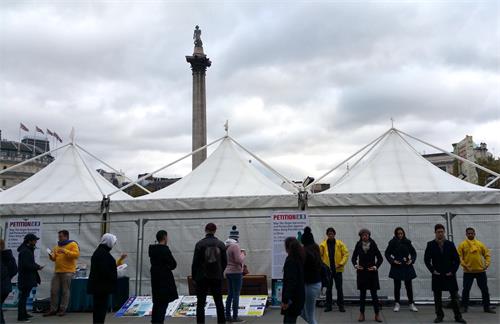 圖1-2：二零一八年十月二十七日，法輪功學員在倫敦特拉法加（Trafalgar Square）廣場北平台發放真相傳單、煉功、講真相、徵簽反迫害
