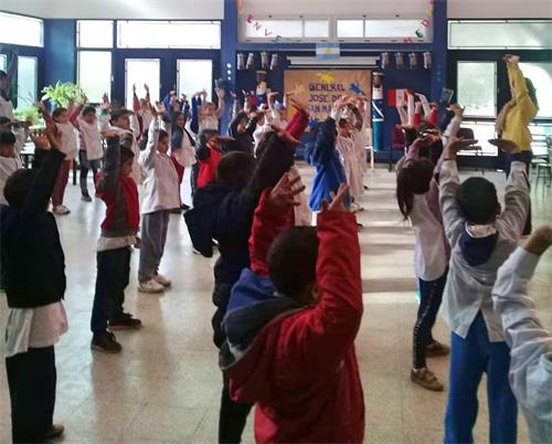 '圖2～3：二零一八年七月十三日，布宜諾斯艾利斯法輪功學員在索拉諾鎮的一所學校教授孩子們法輪功功法。'