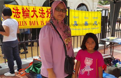 '圖6：Nurul Hayati與她的女兒在法輪大法展位留影。Nurul Hayati在了解中共活摘法輪功學員器官的真相後感到震驚。'