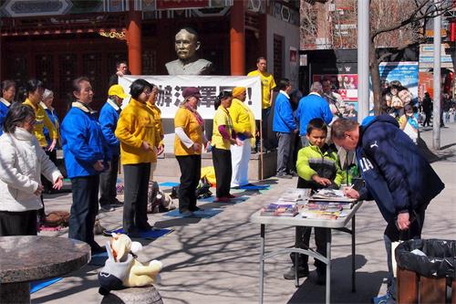 '圖3：2018年4月21日，加拿大蒙特利爾的部份法輪功學員在唐人街中山公園舉行集會和集體煉功，紀念四二五萬人和平上訪十九週年。現場民眾了解真相後，在反迫害徵簽信上簽字。'