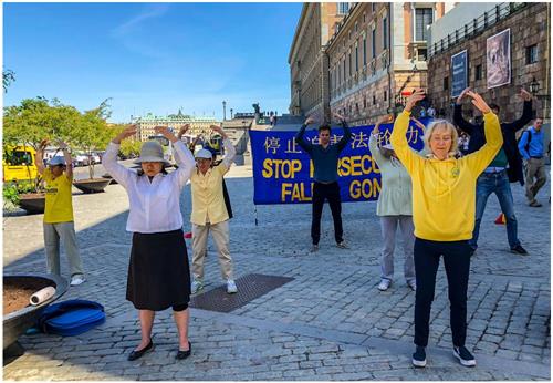 '圖1：瑞典學員在位於瑞典國會大廈和皇宮之間的錢幣廣場上，舉辦揭露中共迫害、講真相活動。學員們在演示祥和的五套功法，向過往民眾展示法輪大法的美好。'