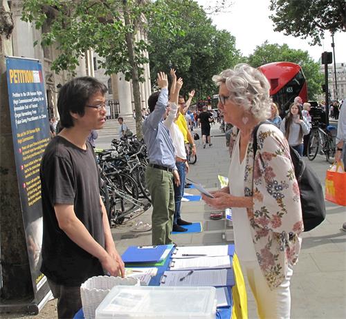 圖10：二零一八年六月二十三日，在倫敦聖馬丁廣場，想學功的蘇珊（Susan）向法輪功學員深入了解真相。