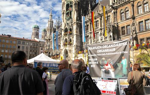 圖1：二零一九年十月一日，德國法輪功學員在慕尼黑瑪琳廣場設立真相點，傳播法輪功的真相。披露中共活體摘取法輪功學員器官的大型橫幅在鬧市中非常醒目。