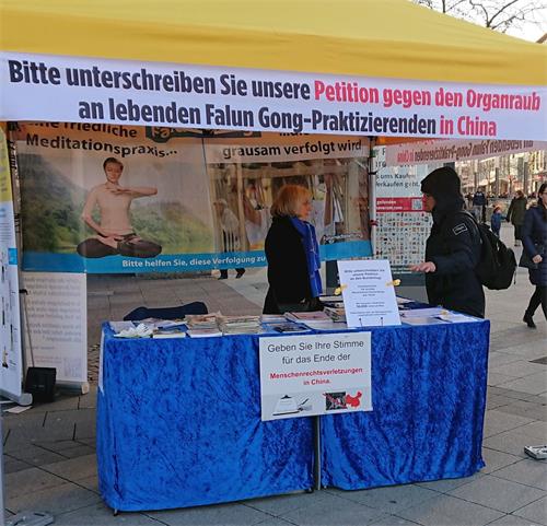'圖1～2：二零一九年十二月十日國際人權日這一天，人們在德國漢諾威的法輪大法信息展位前了解情況，並簽署反對中共活摘器官的請願書。'