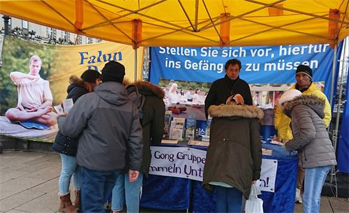 '圖1～2：二零一九年十二月七日，法輪功學員在德國漢堡瑞生丹橋設立真相點，民眾雨中簽名，支持反迫害。'